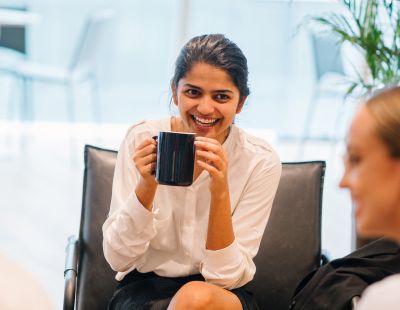 Kvinna dricker kaffe på kontoret