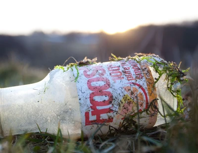 En glasflaska ligger slängd i naturen