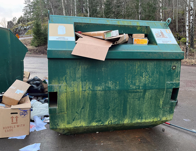 Skräp på marken intill en återvinningsstation