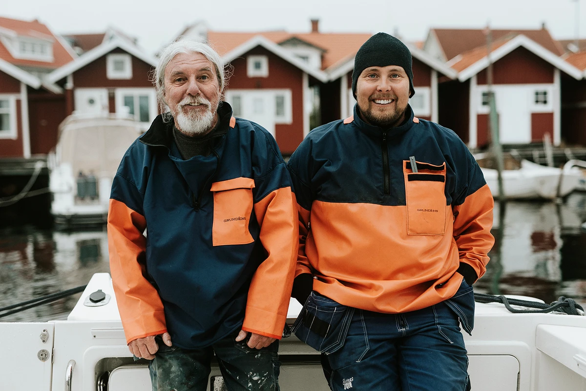 Två fiskare står framför fiskebodar