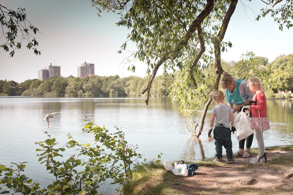 En kvinna och två barn plockar skräp vid en sjö