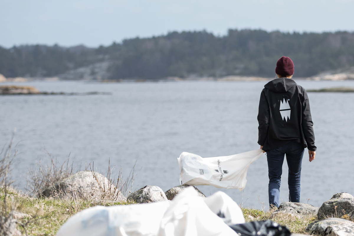Person går på Bohusklippa med skräpplockarpåse