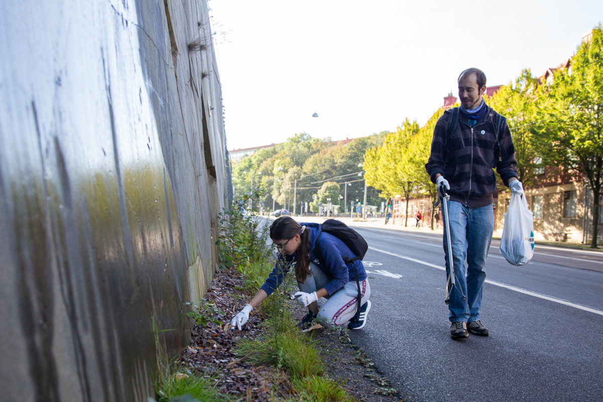 Två personer plockar skräp längs en gata i Göteborg