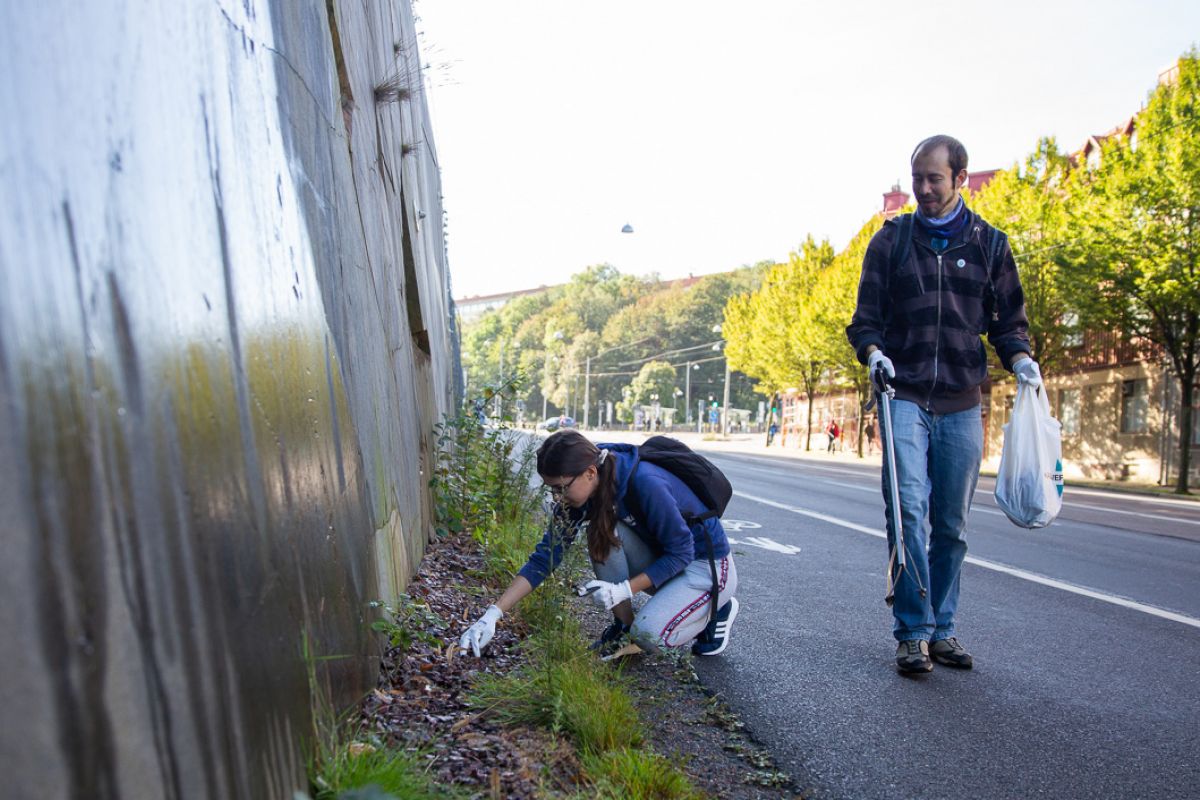 Två personer plockar skräp längs en gata i Göteborg