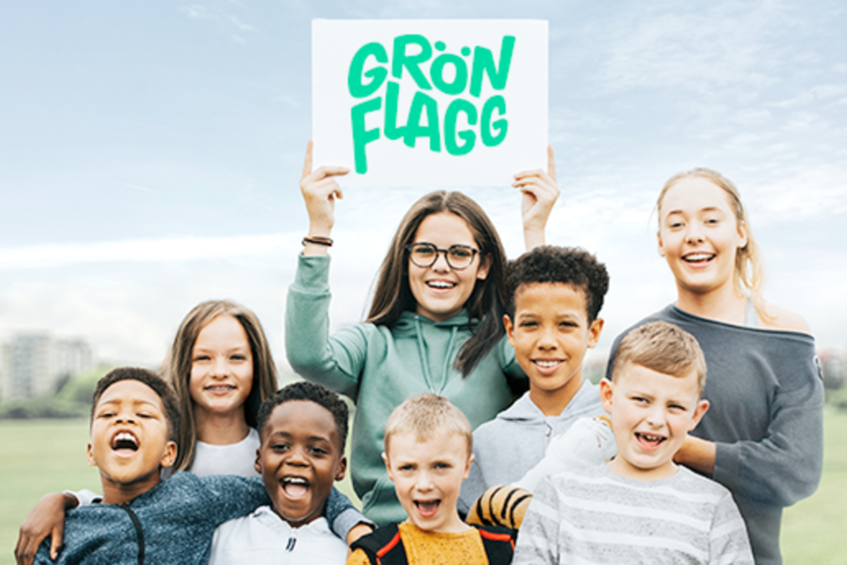 Barn håller upp en skylt med Grön Flagg