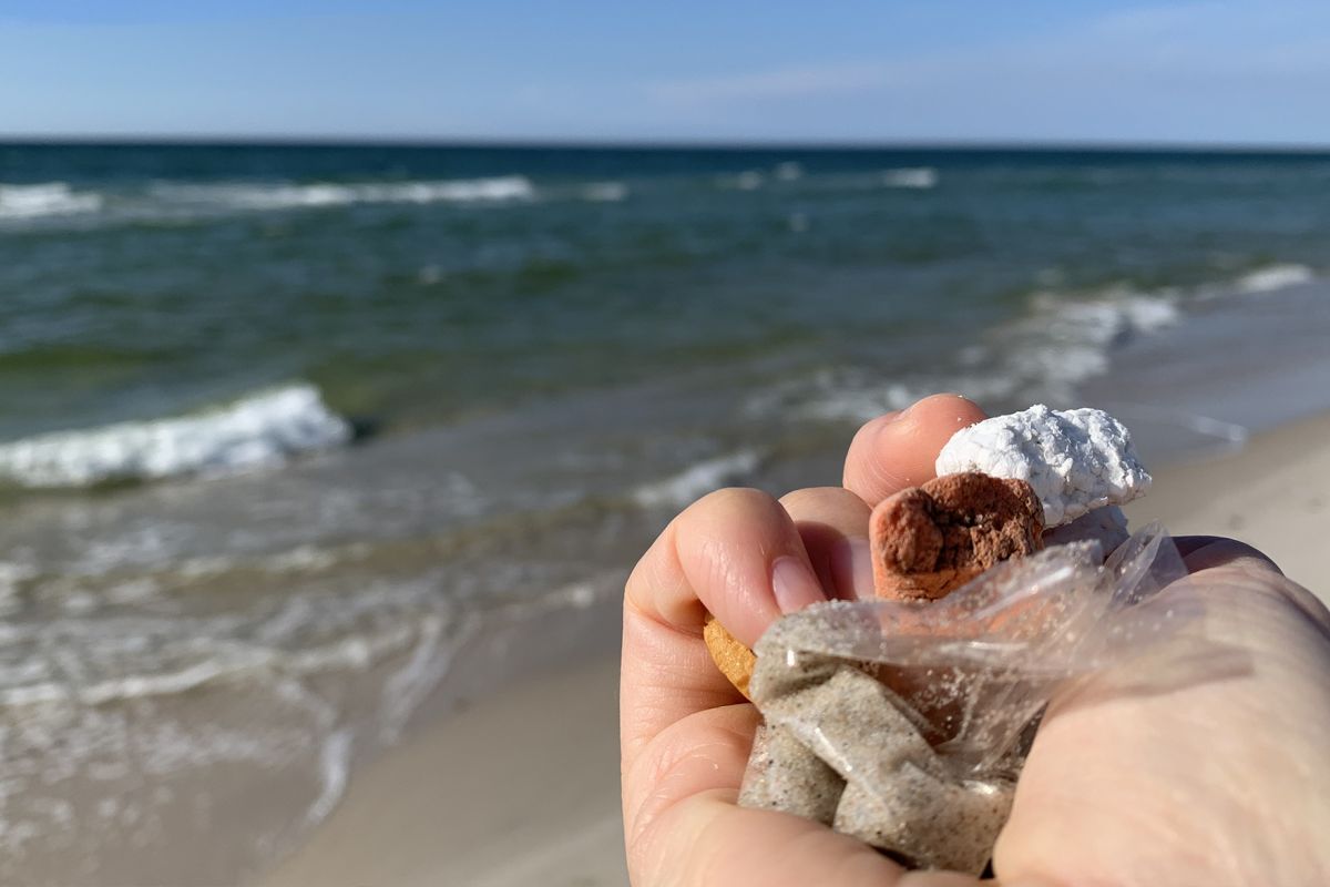 hand med plast framför hav