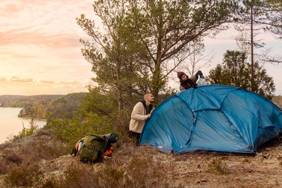 Tre personer sätter upp ett tält.