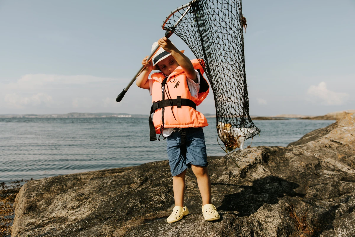 Pojke fiskar upp skräp i havet