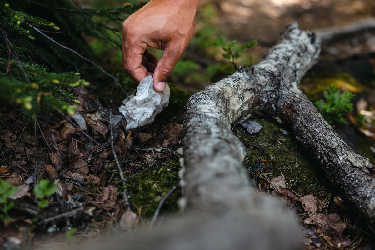 Hand som tar upp skräp i naturen