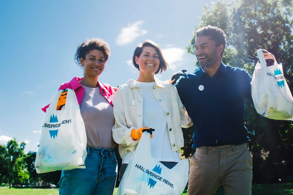 Tre glada skräpplockare i en park