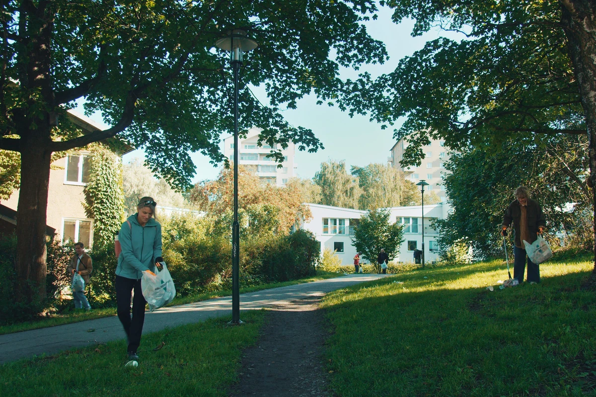 Två personer plockar skräp i en park