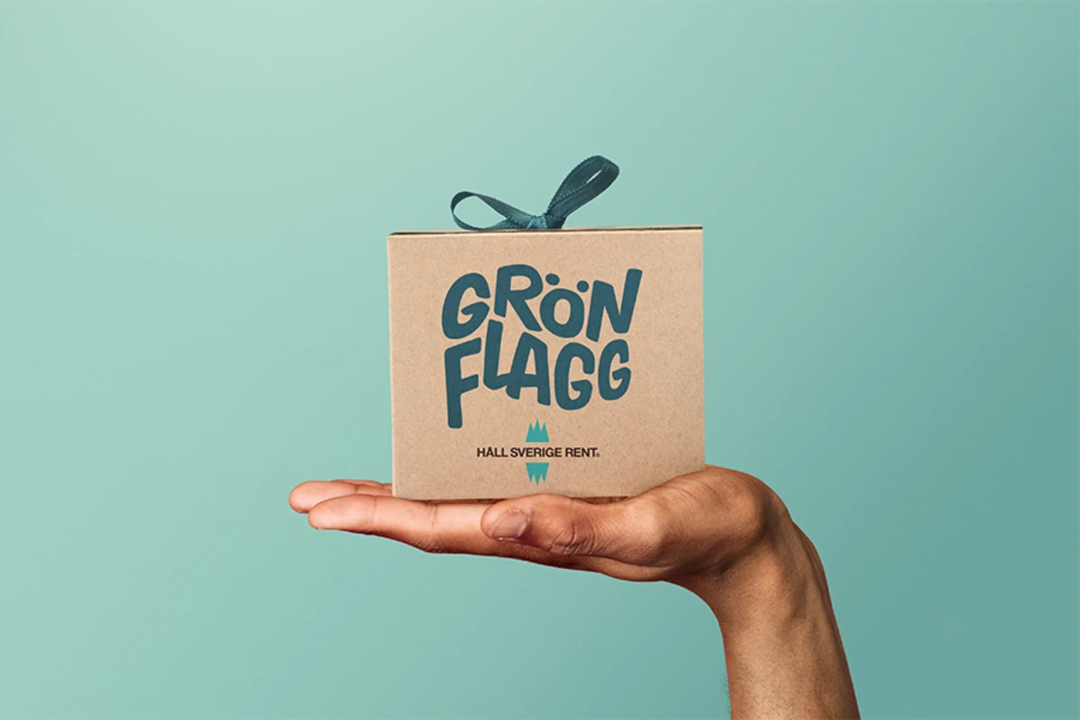Hand håller i ett paket som det står Grön Flagg på