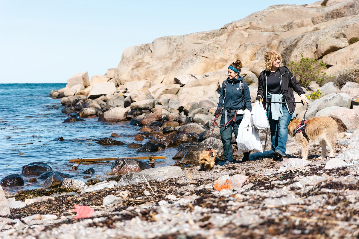 Två personer plockar skräp på stranden