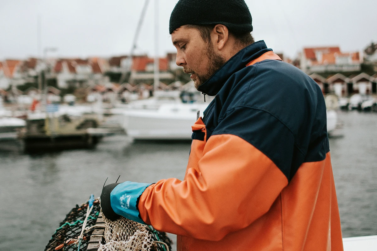 Man står vid vattnet och håller i en hummertina