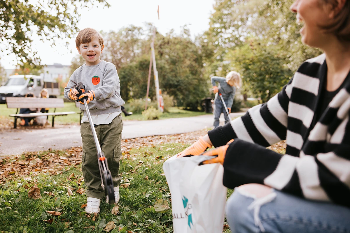 Pojke plockar skräp med mamma i park