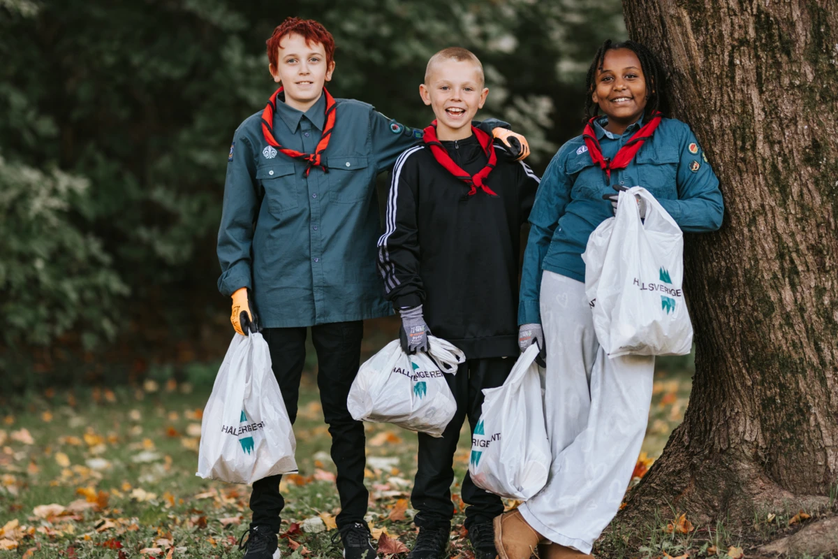 Tre scouter håller i skräppåsar