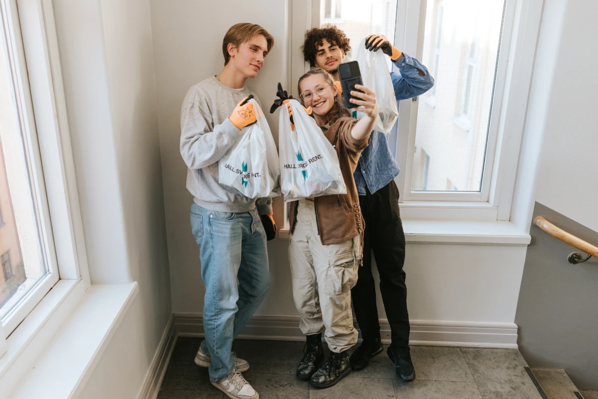 Tre elever tar selfies tillsammans med skräppåsar