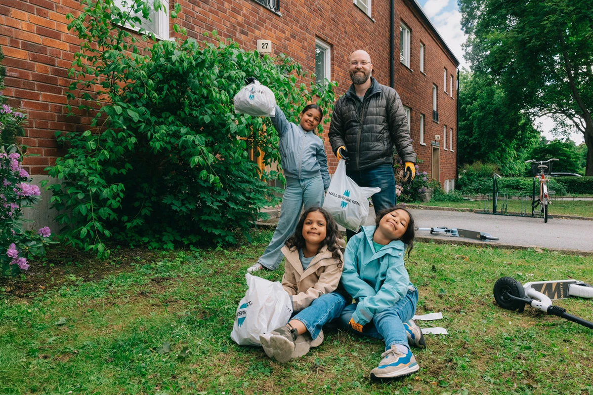 pappa plockar skräp med sina tre döttrar utanför sin bostad