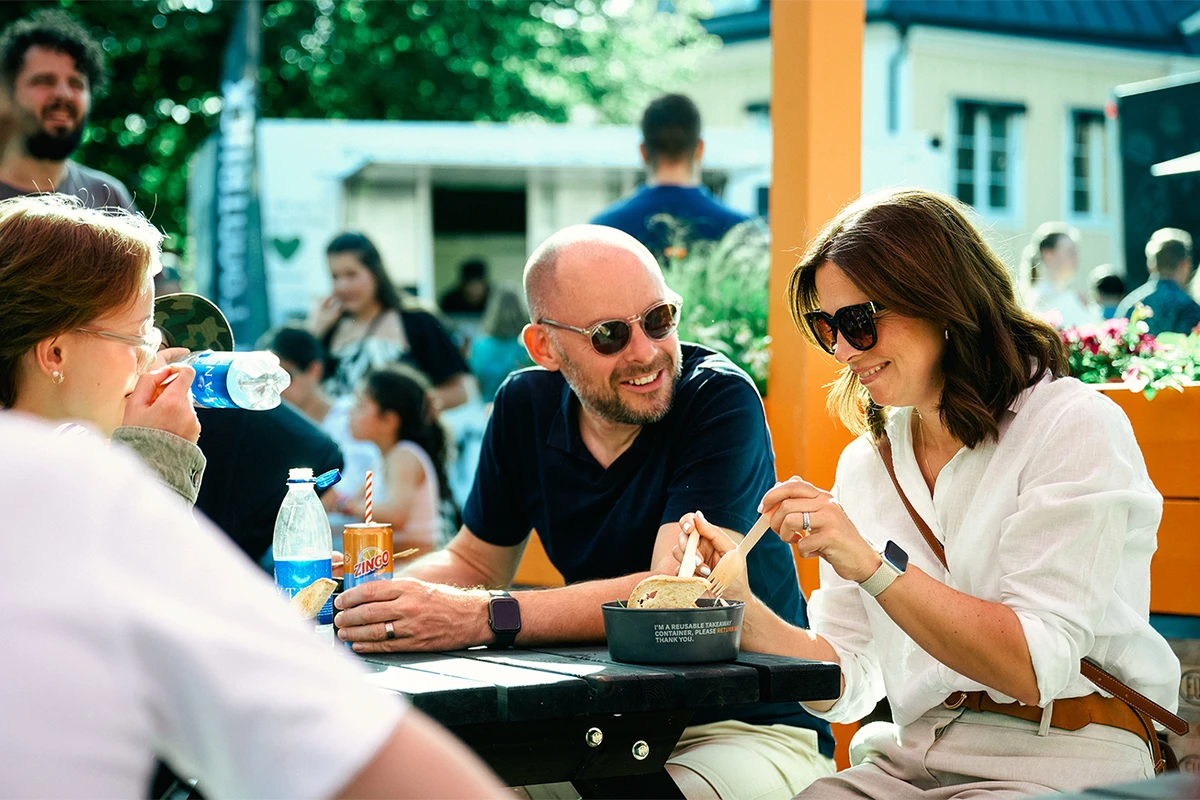 Glada människor som äter take away-lunch från flergångstallrik