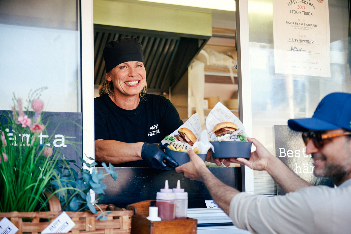 Kvinna i foodtruck serverar mat på flergångstallrik