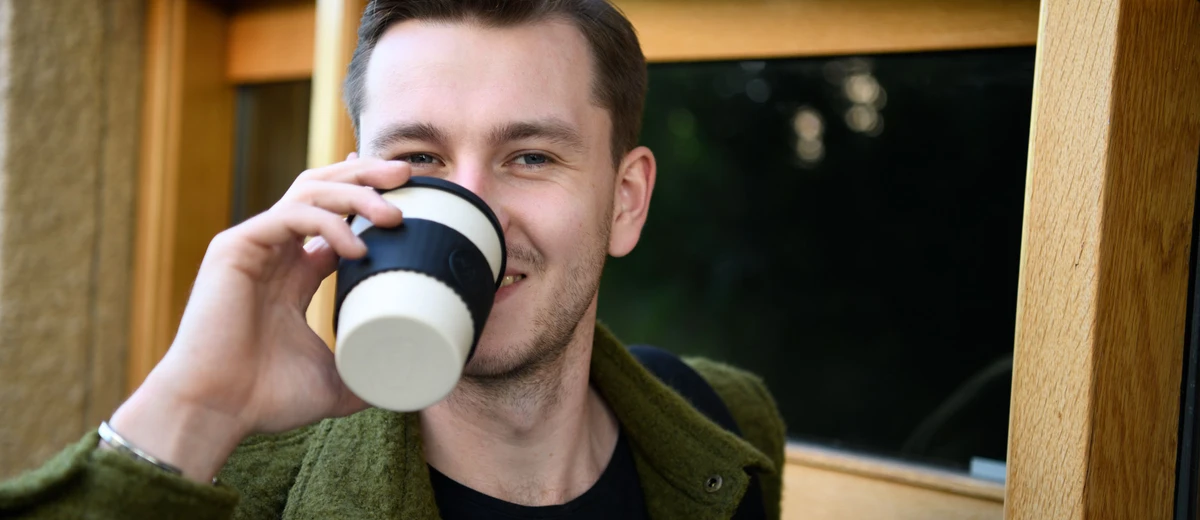 Kille dricker ur en flergångsmugg i bambu.