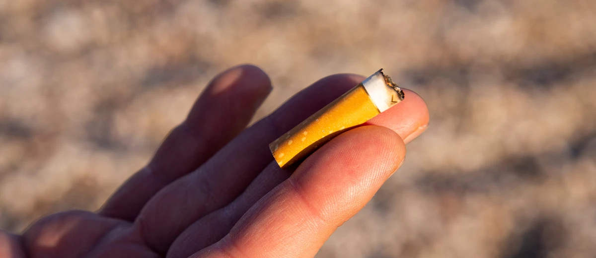 En hand håller upp en fimp