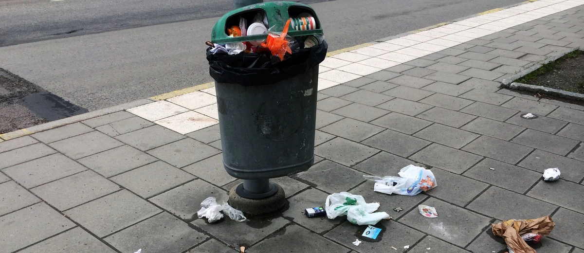 Överfull papperskorg i stadsmiljö