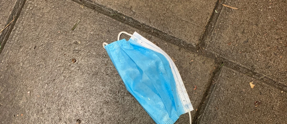 Ett munskydd ligger som skräp på gatan