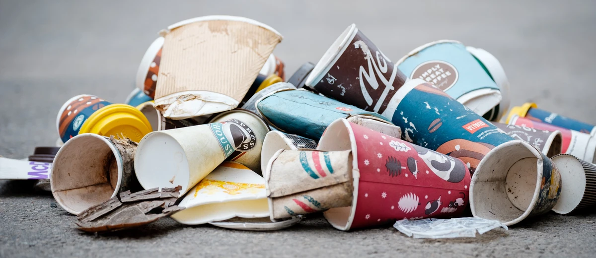 Skräpiga engångsmuggar ligger i en hög på marken