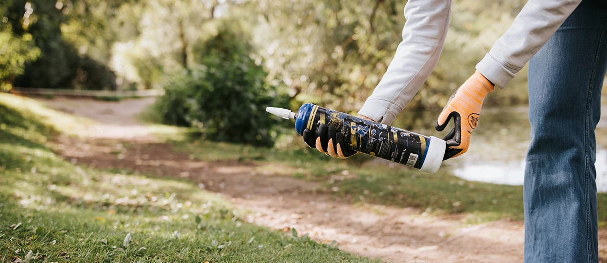 Kvinna plockar upp använd lustgastub i naturen