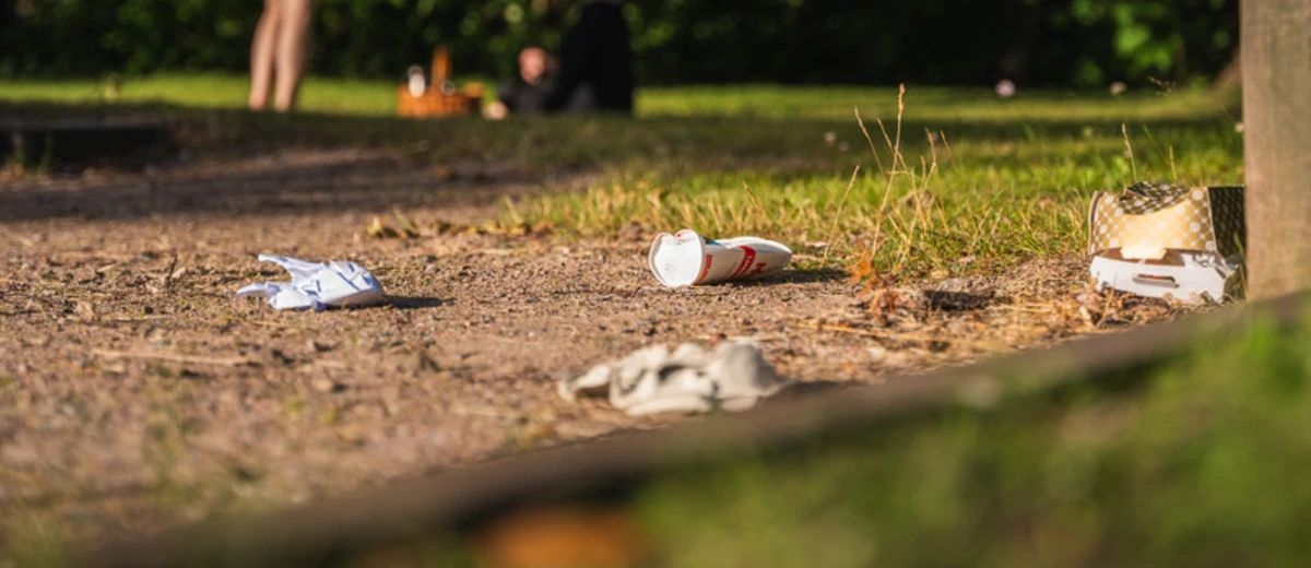 Engångsförpackningar ligger slängda på marken i en park