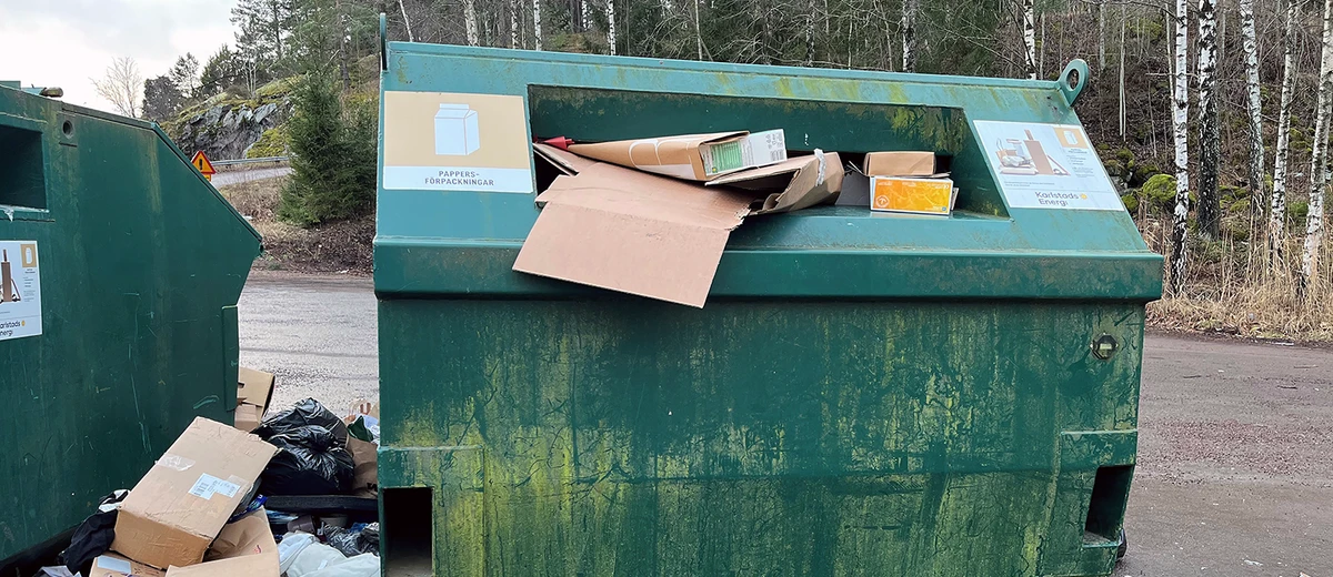 Skräp på marken intill en återvinningsstation