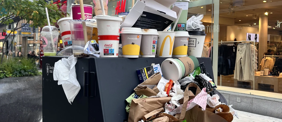 Skräp väller ut från en överfull papperskorg på stan