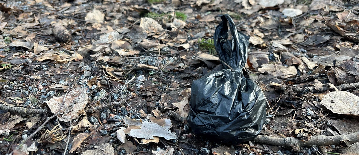 Hundbajspåse ligger och skräpar på marken