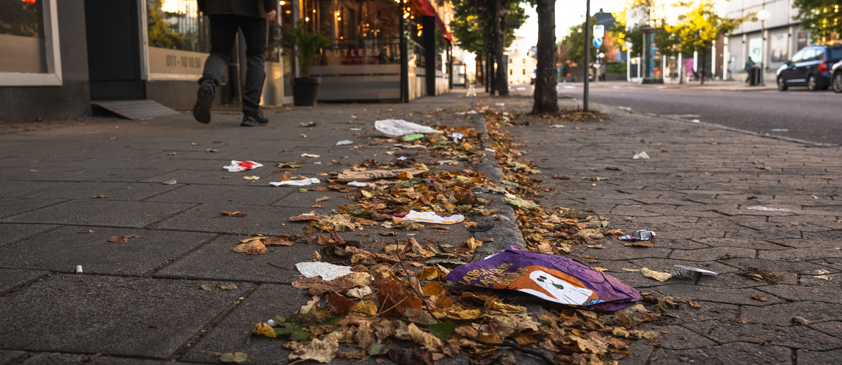 Skräp ligger på marken i höstig stadsmiljö