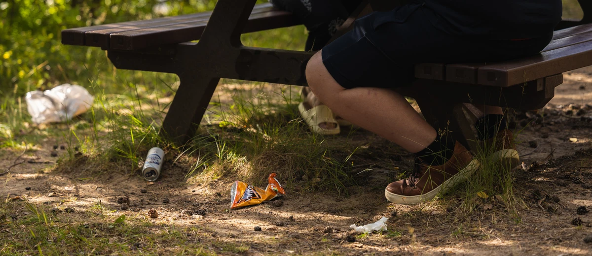 Skräp ligger på marken under parkbänk