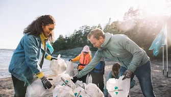 Kusträddare samlar påsar med skräp i en hög på en strand