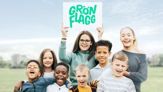 Barn håller upp en skylt med Grön Flagg