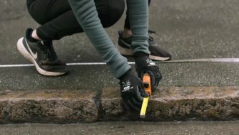 En person mäter avstånd från trottoarkant för att genomföra en skräpmätning