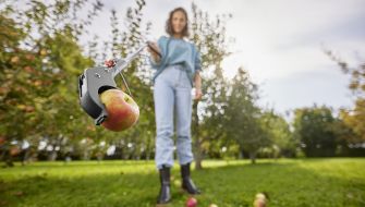 Kvinna plockar äpple med griptång