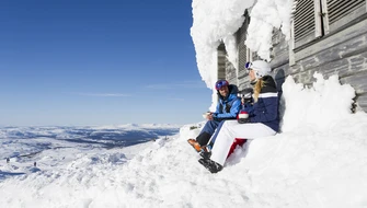 Två personer som fikar vid en skidbacke