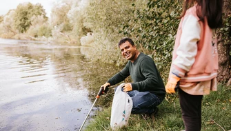 Glad man plockar skräp från vattnet