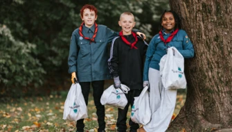 Tre scouter håller i skräppåsar