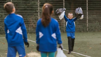 Barn i ett fotbollslag visar upp skräppåsar