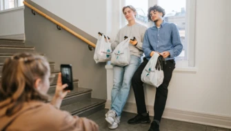 Tre elever står i ett trapphus och tar bilder av sig själva med skräppåsar