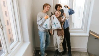 Tre elever tar selfies tillsammans med skräppåsar