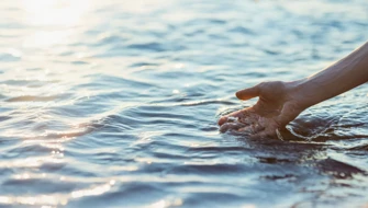En hand som känner på vattnet i havet