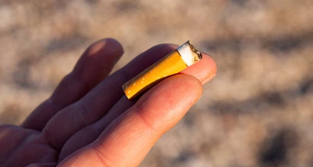 En hand håller upp en fimp