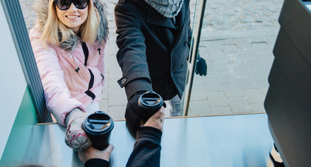 Två unga personer tar emot varsin take away-mugg