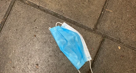 Ett munskydd ligger som skräp på gatan